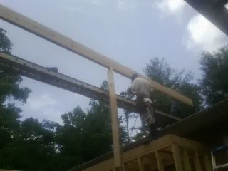 Carpenter setting a ridge beam over a new addition frame in Hardwick