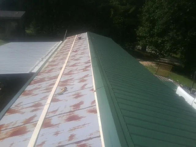 Old rusted panels beside newly installed green metal roofing — Wind Damage Roof Repair by Roofing Brothers in Hardwick