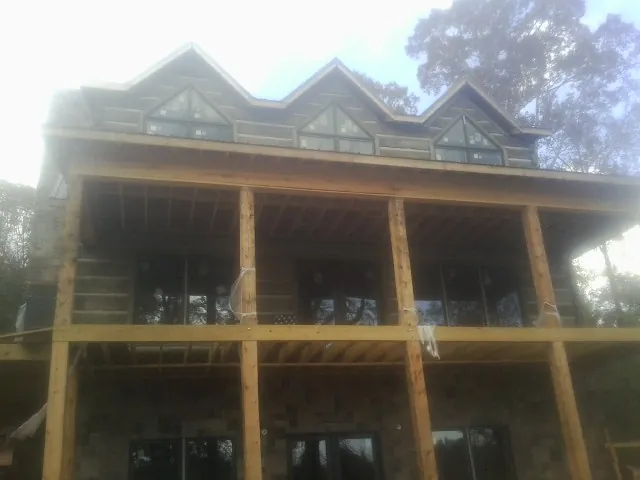 Dormers and porch framing on a large log home under construction — Roof Coating work by our crew in Hardwick