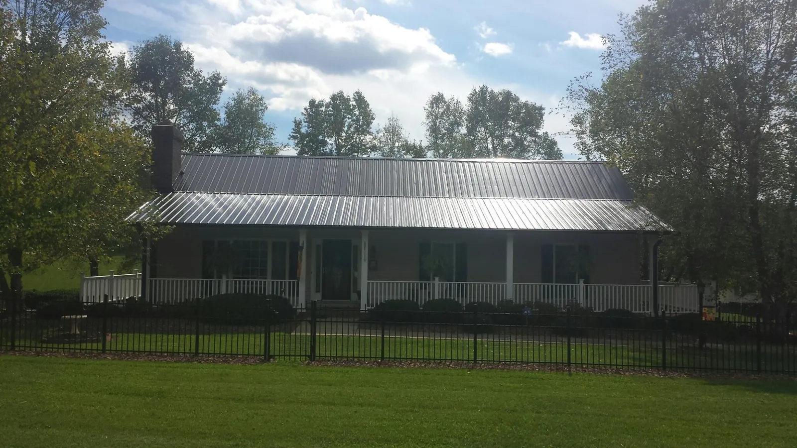 Gray metal roof on a brick ranch with a full width front porch — Gutter Guard Installation work by our crew in Hardwick
