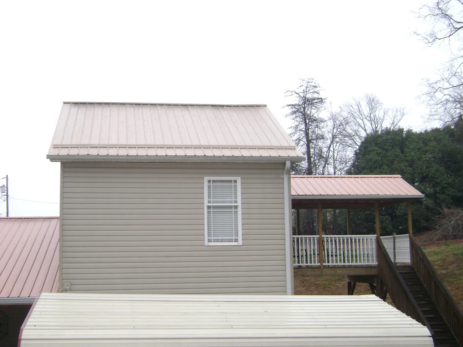Tan metal roofs on a two story addition and attached porch, from a Roof Replacement job in Hardwick