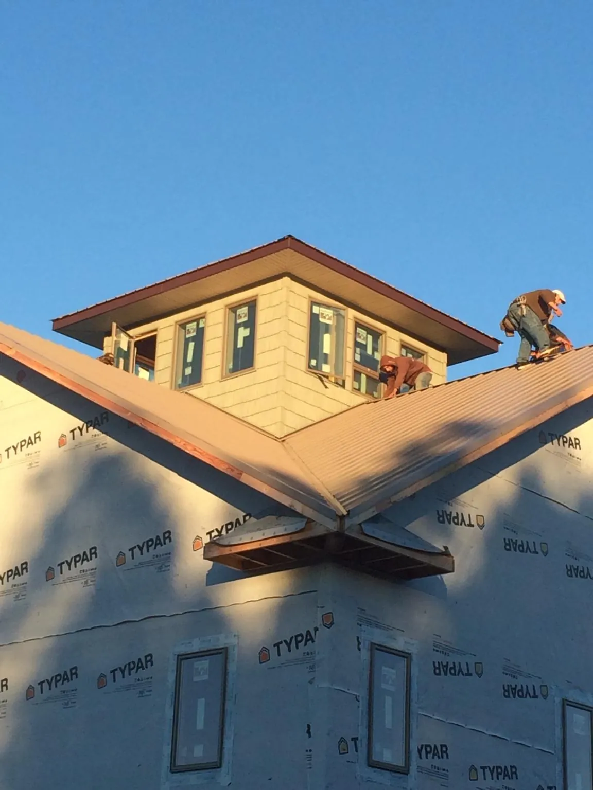 Roofers working around a rooftop cupola on a new metal roof at sunset — Roof Waterproofing in Hardwick by Roofing Brothers